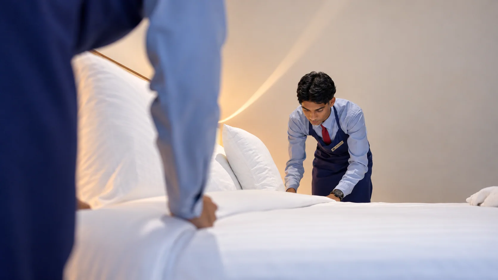 Hospitality student practicing bed presentation with a colleague