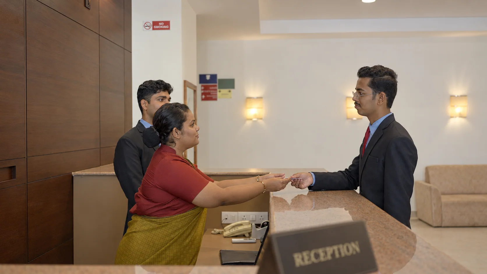 Guest and receptionist exchanging a key card at a hotel front desk